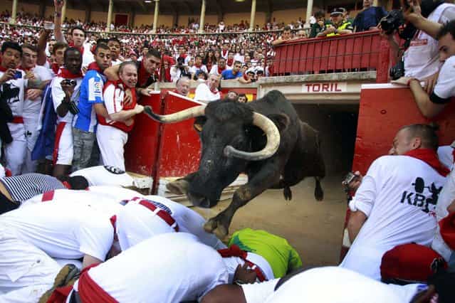 A fighting cow leaps over revelers into the bull ring after the fourth running of the bulls at the San Fermin festival in Pamplona July 10, 2013. (Photo by Joseba Etxaburu/Reuters)