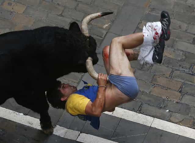 A runner gets gored by a bull on Estafeta street during the sixth running of the bulls of the San Fermin festival in Pamplona July 12, 2013. Four runners were gored in a run that lasted four minutes and fifty seven seconds, according to local media. (Photo by Susana Vera/Reuters)