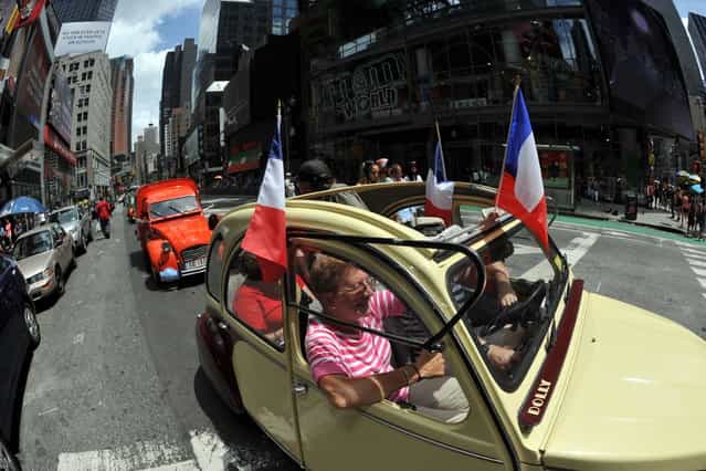 A parade of Citroen 2CV cars from the Greater New York Citroen and Velosolex Touring Club passes through Time's Square on Bastille Day July 14, 2013 in New York. (Photo by Stan Honda/AFP Photo)