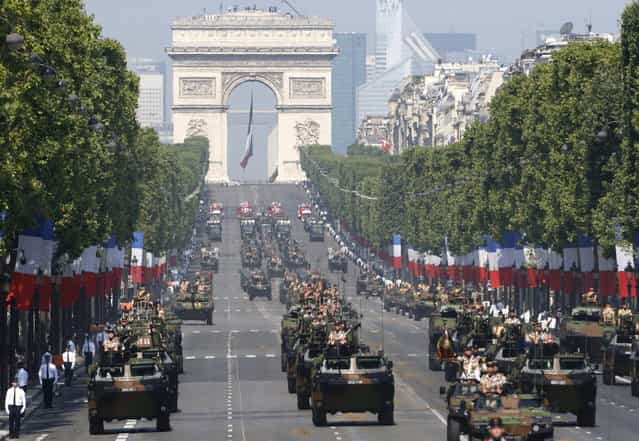 French soldiers stand in an armored vehicle during the Bastille Day parade in Paris, Sunday, July 14, 2013. Troops from 13 African countries who backed France in a war against al-Qaida-linked extremists in Mali marched with the French military during the Bastille Day parade in Paris on Sunday to honor their role in the conflict. The Arc de Triomphe is seen in background. (Photo by Francois Mori/AP Photo)