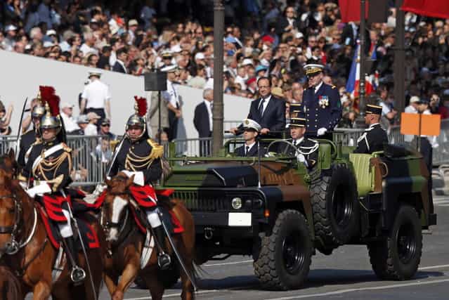France's President Francois Hollande stands at attention in the command car as he reviews the troops while descending from the Champs Elysees at the start of the traditional Bastille Day military parade in Paris July 14, 2013. (Photo by Benoit Tessier/Reuters)