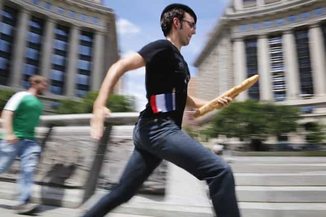 People compete in a lighthearted French baguette relay race as part of a Bastille Day promotion at the La Maison Paul restaurant in Washington, July 14, 2013. The restaurant says the bread in their Washington restaurants comes from a [mother dough] starter brought directly from Lille, France. (Photo by Jonathan Ernst/Reuters)