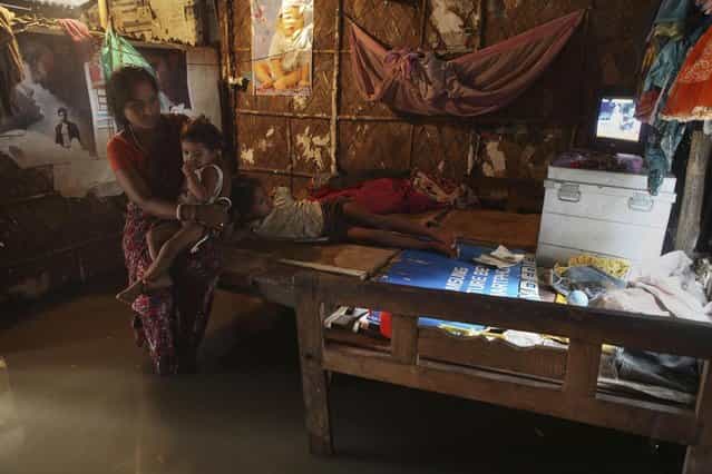 An Indian girl watches television as her mother sits with her sister on a bed inside a waterlogged rented house in Gauhati, India, Tuesday, July 16, 2013. (Photo by Anupam Nath/AP Photo)
