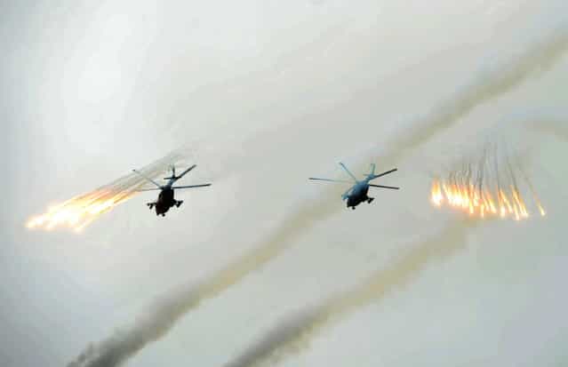 Russian Army helicopters fire flares over Sakhalin Island during military exercises on Tuesday, July 16, 2013. (Photo by Alexei Nikolsky/AP Photo/RIA Novosti/Presidential Press Service)