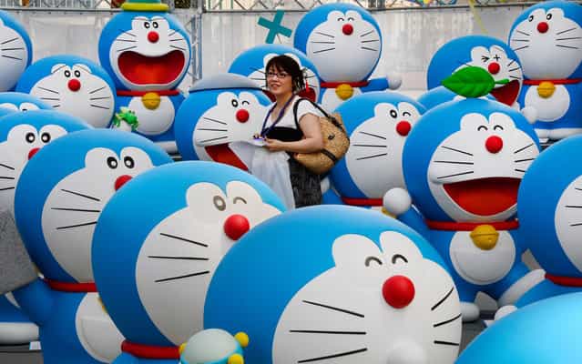 A journalist walks amid life-size figures of Doraemon on the roof of the Tokyo Tower Foot Town during the press preview of the Fujiko F Fujio Exhibition on July 18, 2013. The exhibition will be held from July 19 to October 6. (Photo by Toru Yamanaka/AFP Photo)
