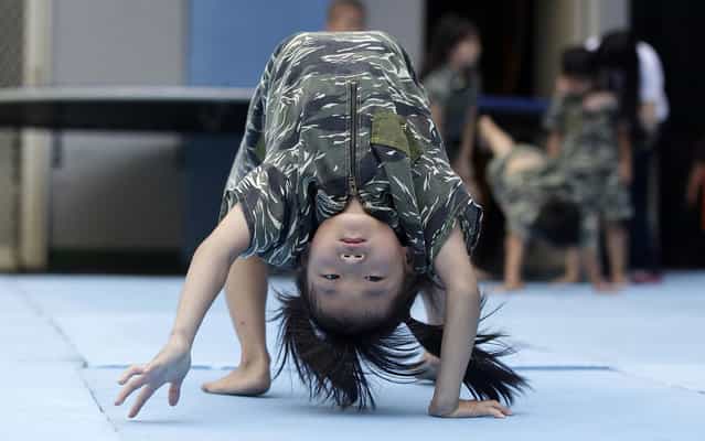 Kids in camouflage clothes attend a physical training session in a kindergarten in Taichung, central Taiwan, July 15, 2013. A kindergarten in Taiwan provides physical training sessions, a series of exercises that combines marine drills and gymnastics for pre-school and school aged kids. The training helps children grow well in both mind and body, according to the principal. (Photo by Pichi Chuang/Reuters)