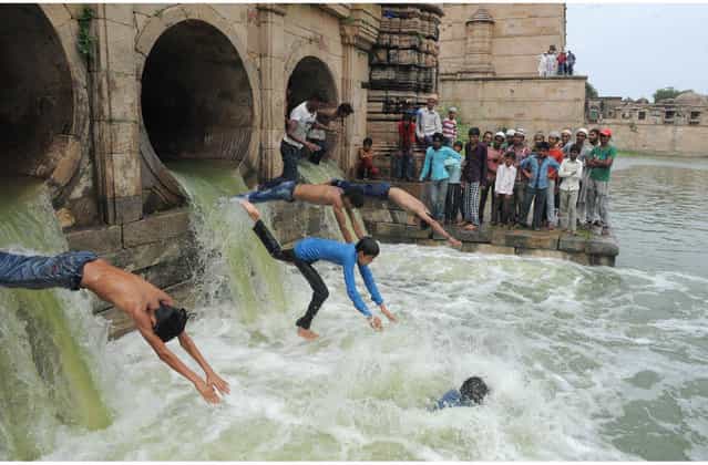Indian Muslim youth dive as flood waters enter the tank of the 600 year old Sarkhej Roza architectural complex, which has been dry for the last seven years, in Ahmedabad on July 14, 2013. The Sarkhej Roza is maintained by the Archeological Survey of India and this tomb and mosque of a Sufi saint are known in this region as [Ganj Bakhsh]. (Photo by Sam Panthaky/AFP Photo)