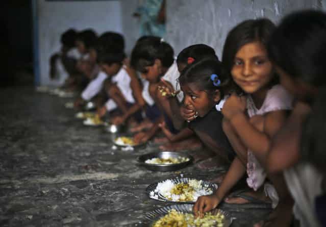 School children eat their free mid-day meal, distributed by a government-run primary school, at Brahimpur village in Chapra district of the eastern Indian state of Bihar July 19, 2013. Police suspect that India's worst outbreak of mass food poisoning in years was caused by cooking oil that had been kept in a container previously used to store pesticide, the magistrate overseeing the investigation said on Friday. (Photo by Adnan Abidi/Reuters)