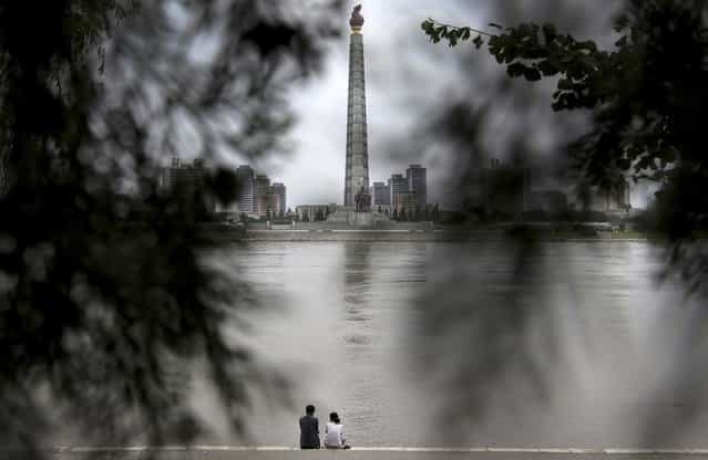 A North Korean couple sits by a river with a view of Ju Che Tower from Kim Il Sung Square on Sunday, July 21, 2013, downtown Pyongyang, North Korea. (Photo by Wong Maye-E/AP Photo)