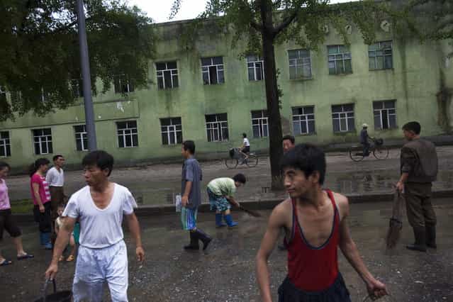 North Koreans clean a street after a heavy rainfall in Kaesong, North Korea on Monday, July 22, 2013. (Photo by David Guttenfelder/AP Photo)