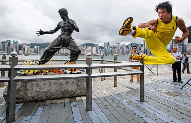 Chinese actor Mei Zhiyong dressing as the late Hong Kong Kung Fu star Bruce Lee performs in front of the bronze statue in Hong Kong Saturday, July 20, 2013 to commemorate the 40th anniversary of the death of Lee. The late superstar Bruce Lee is best-known for the kung fu skills he displayed in his movies, but his daughter hopes that more people take the effort to understand his teachings and life philosophy. Marking his death 40 years ago on July 20, the Hong Kong government has teamed up with the Bruce Lee Foundation to put together an exhibition to showcase the late star's life, from his famous yellow tracksuit he wore in the movie [Game of Death], to his writings and drawings. (Photo by Kin Cheung/AP Photo)