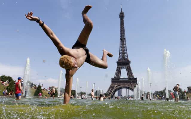 A man jumps in a fountain of the Trocadero Square in front of the Eiffel Tower as hot summer temperatures continue in Paris, on July 22, 2013. (Photo by Benoit Tessier/Reuters)