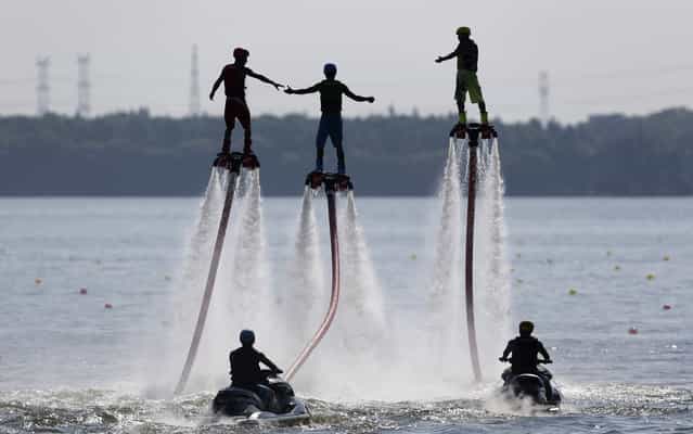 People riding on water-powered jet-boards perform at Donghu lake in Wuhan in the Hubei province of China on July 25, 2013. (Photo by Darley Shen/Reuters)