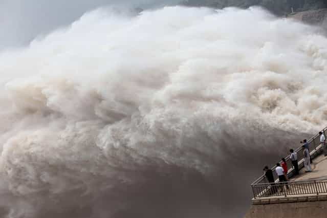 This picture taken on July 23, 2013 shows people watching on the edge of the Xiaolangdi reservoir as Yellow River floodwaters are released for the second time since the end of June in Xiaolangdi, in central China's Henan province. At least 295 people have been confirmed dead or missing after rainstorms and Typhoon Soulik hit China, causing floods, landslides and buildings to collapse, the government said on July 15. (Photo by AFP Photo)