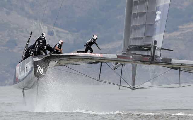 Trimmer James Dagg, right, and grinder Winston Macfarlane, second from right, run to the other side of Emirates Team New Zealand as skipper Dean Barker, left, watches during an America's Cup challenger series sailing race against Luna Rossa Challenge of Italy, Tuesday, July 23, 2013, in San Francisco. Emirates Team New Zealand won the race. (Photo by Eric Risberg/AP Photo)