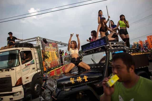 Pole dancers perform on a jeep during the temple fair on July 21, 2013 at Dounan of Yunlin County, Taiwan. The fair is a traditional festival in Taiwan which includes cultural and community activities such as drawing, dancing and guided walks of the temple. (Photo by Lam Yik Fei/Getty Images)