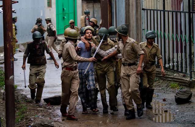 Indian police officers arrest a Kashmiri boy protesting during curfew in Srinagar, India, Saturday, July 20, 2013. Authorities in Indian-administered Kashmir Saturday decided to extend a curfew following violent protests over the deaths of four people in shooting by the paramilitary police. Although the situation remained largely peaceful on Saturday, clashes between stone-throwing mobs and security forces until late Friday left 59 people, including 49 police and paramilitary, injured, a police spokesman said. (Photo by Dar Yasin/AP Photo)