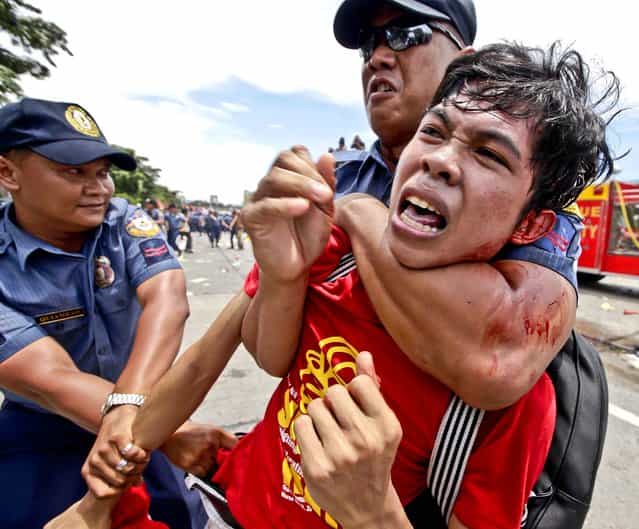 Police detain a protester during a clash as they attempt to march closer to the House of Representatives where Philippine President Benigno Aquino III is set to deliver his fourth State-of-the-Nation Address, on July 22, 2013. He is expected to dwell on the gains of his administration particularly on the robust economy but the protesters see otherwise especially on the increasing prices of oil and basic services as water and electricity. (Photo by Bullit Marquez/Associated Press)