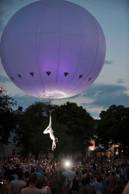 The Dream Engine Heliosphere, an enormous light-filled helium balloon that rises and falls and glides through the sky above the streets of Galwa suspending a stunning balletic aerialist who tumbles and turns from ground level to 20-metres above the audience, on July 24, 2013. (Photo by Andrew Downes)