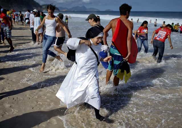 A nun reacts as the tide comes in on Copacabana beach. (Photo by Victor R. Caivano/Associated Press)