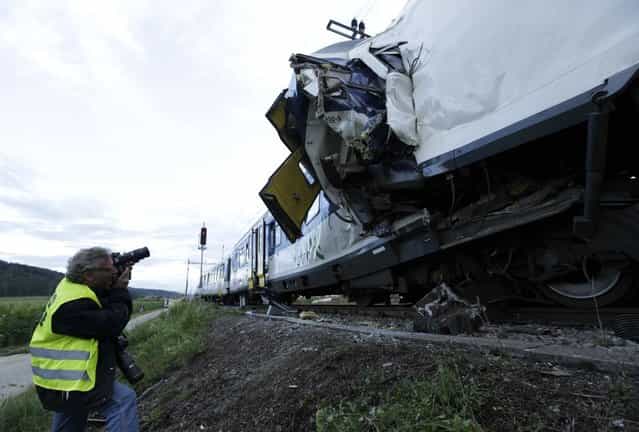 A photographer takes pictures after two Swiss regional trains crashed head on near Granges-Pres-Marnand near Payerne in western Switzerland July 29, 2013. The two trains collided in the Swiss canton of Vaud on Monday evening, injuring about 40 people, four seriously, Swiss news agency ATS reported. There was no immediate report of any deaths in the crash. (Photo by Denis Balibouse/Reuters)