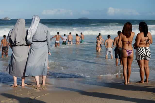 Two Polish nuns look at people bathing as hundreds of thousands of young Catholic pilgrims attend the World Youth Day gathering at Copacabana beach in Rio de Janeiro. (Photo by Yasuyoshi Chiba/AFP Photo)