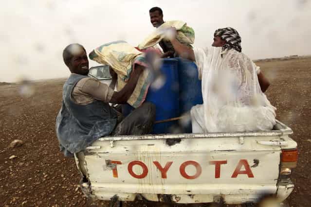 Gold mine workers at the back of a truck take cover from rain as they make their way to a local mine in Al-Ibedia locality at River Nile State, July 30, 2013. (Photo by Mohamed Nureldin Abdallah/Reuters)