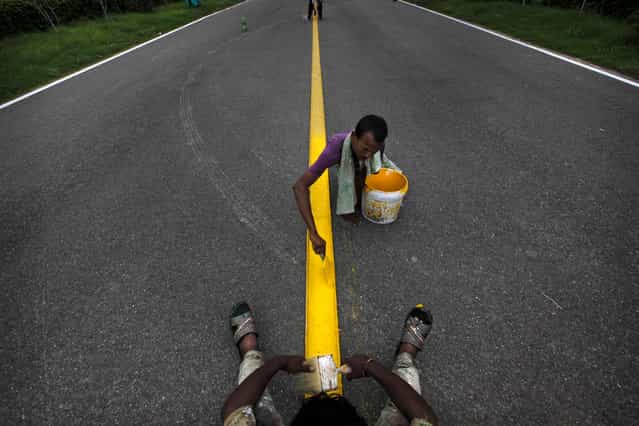 Indian laborers paint the center yellow line at the ceremonial boulevard Rajpath ahead of Independence Day celebrations in New Delhi, India, Wednesday July 31, 2013. India celebrates Independence Day on August 15. (Photo by Manish Swarup/AP Photo)