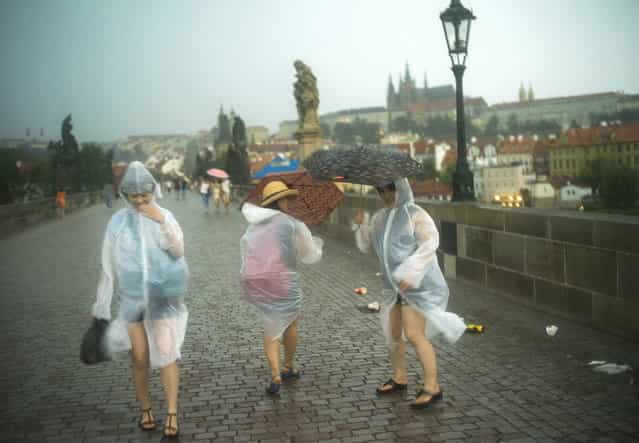 Japanese women walk across the Charles Bridge during a heavy rainfall in Prague on July 29, 2013. (Photo by Michal Cizek/AFP Photo)