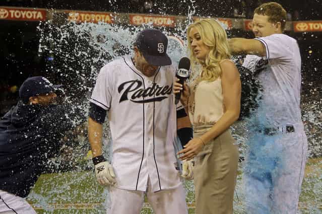 San Diego Padres' Chris Denorfia gets the victory bath from Nick Hundley, right, and Rene Rivera while being interviewed by television reporter Kelly Crull after his two-run walk off home run in the bottom of the ninth inning gave the Padres a 2-1 victory over the Cincinnati Reds in a baseball game in San Diego, Monday, July 29, 2013. (Photo by Lenny Ignelzi/AP Photo)