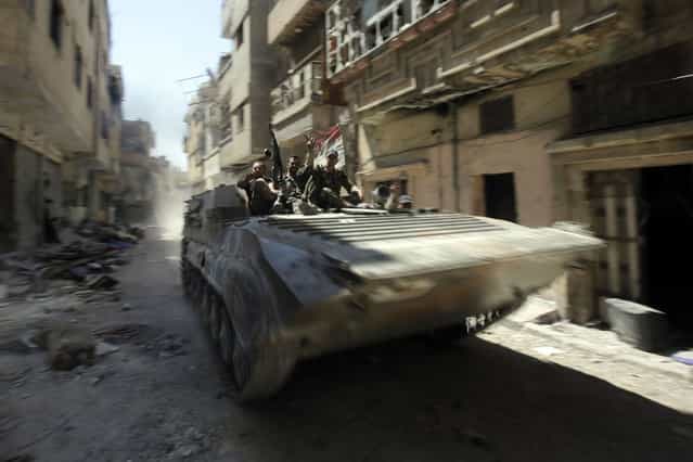 Soldiers of the Syrian government forces patrol on a tank in a devastated street on July 31, 2013 in the district of al-Khalidiyah in the central Syrian city of Homs. The Syrian government announced the capture of Khalidiyah, a key rebel district in Homs, Syria's third city and a symbol of the revolt against President Bashar al-Assad. (Photo by Joseph Eid/AFP Photo)
