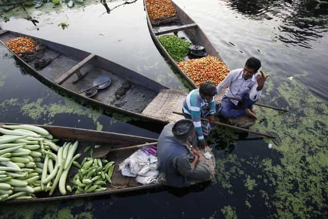 Kashmiri men sit on boats loaded with vegetables at the floating vegetable market on Dal Lake in Srinagar, India, at dawn Sunday, July 28, 2013. Vegetables are grown in numerous floating gardens around the lake, and sold from boats at the market. A variety of different vegetables are grown through all four seasons, making the floating market a daily event throughout the year. (Photo by Greg Baker/AP Photo)