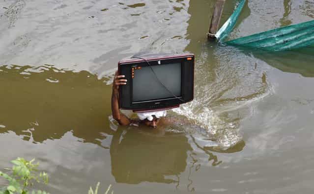 A flood-affected man carries his television set to a safer place, after heavy monsoon rains caused a rise in the water levels of the river Ganges, in the northern Indian city of Allahabad August 1, 2013. (Photo by Jitendra Prakash/Reuters)