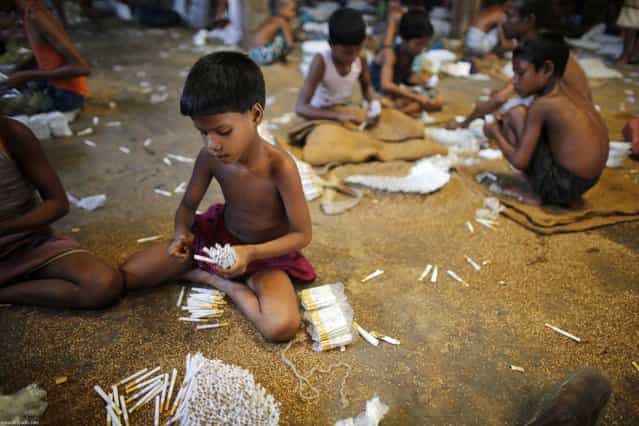 Children fill up empty cigarettes manually with locally grown tobacco in a small bidi (cigarette) factory at Haragach in Rangpur district, Bangladesh July 11, 2013. According to a 2012 study by US-based NGO, Campaign for Tobacco-Free Kids, over 45,000 people in Bangladesh are employed in manufacturing inexpensive cigarettes known as bidis and this number includes &ldquo;many women and children working in household based establishments where they make low wages and live in poverty.&rdquo; A 2011 research paper about bidi workers in Bangladesh, published in the journal Tobacco Control, says that working conditions can involve poor ventilation and exposure to tobacco dust, which can cause a range of health problems including respiratory and skin diseases. International attention has been focused on workers&rsquo; safety in Bangladesh since the disaster at Rana Plaza, a garment factory complex which collapsed in April, killing 1,132 workers. (Photo by Andrew Biraj/Reuters)