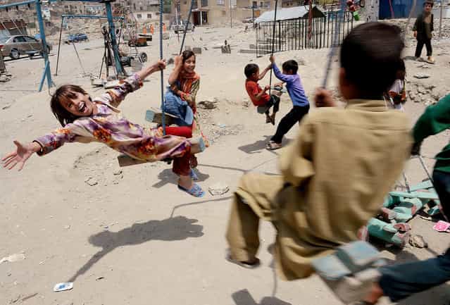 Afghan children play on a swing near a cemetery in Kabul on July 31, 2013. Civilian casualties in the Afghan war rose 23 percent in the first half of this year due to Taliban attacks and increased fighting between insurgents and government forces, the UN said on July 30. (Photo by Shah Marai/AFP Photo)