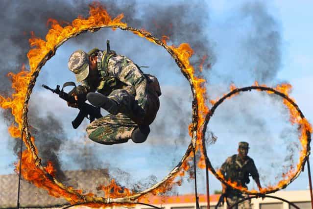 A soldier from the People's Liberation Army jumps through a ring of fire as part of training during the PLA Army Day in Wenzhou, Zhejiang province, on August 1, 2013. (Photo by Reuters)