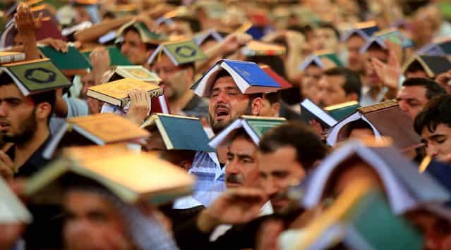 Shi'ite pilgrims place copies of the Koran on their heads during the ceremony marking the anniversary of the death of Imam Ali at his shrine in the holy city of Najaf, on July 30, 2013. (Photo by Ahmad Mousa/Reuters)