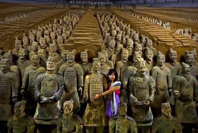 A woman hugs a terracotta warrior replicas as she poses for a souvenir photo at the Museum of Qin Terracotta Warriors and Horses in Xi'an, in central China's Shaanxi province, on July 30, 2013. Thousands of the soldiers that were buried in the tomb of the Emperor Qin Shihuang, who ruled China between 221-210 B.C., are displayed in Xi'an. (Photo by Andy Wong/Associated Press)