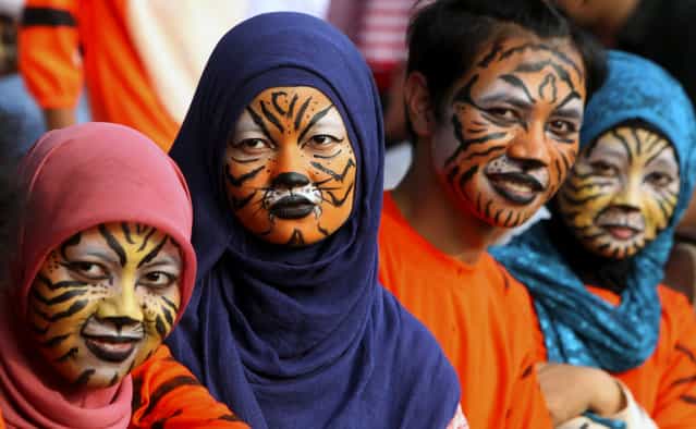 Activists with faces painted to resemble tigers, take part in a protest against Sumatran tiger trade that marks the Global Tiger Day, in Jakarta, Indonesia, Monday, July 29, 2013. Sumatran tiger is the world's most critically endangered tiger subspecies with fewer than 400 remain in the wild and may become extinct in the next decade due to poaching and habitat loss. (Photo by Tatan Syuflana/AP Photo)