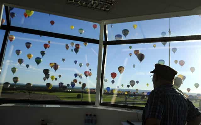 Hot-air balloons are pictured from a control tower while flying over Chambley-Bussieres, eastern France, on July 31, 2013, to try to set a world record with 408 balloons in the sky, as part of the yearly event [Lorraine Mondial Air Ballons], an international air-balloon meeting. (Photo by Jean-Christophe Verhaegen/AFP Photo)