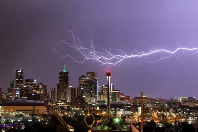 A huge blast of purple-tinged lightning streaks across a row of skyscrapers in Denver, Colorado. (Photo by Greg Thow/Barcroft Media)