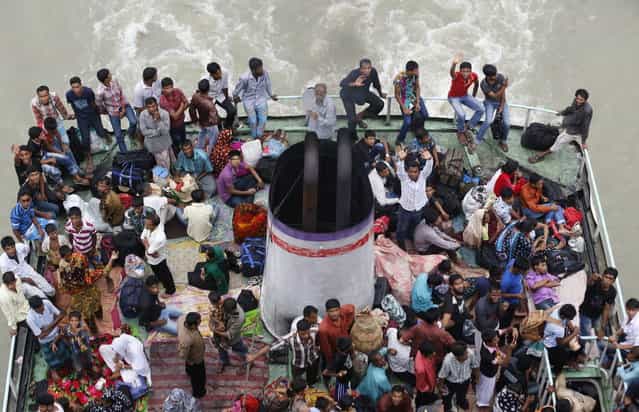 People look on from an overcrowded passenger boat navigating through the Buriganga River in Dhaka August 7, 2013. Millions of residents in Dhaka have started the exodus home from the capital city ahead of the Eid al-Fitr holiday, which marks the end of the fasting month of Ramadan. (Photo by Andrew Biraj/Reuters)