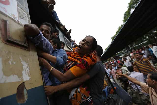 Passengers spill out from the train door as they travel aboard an overcrowded train at a railway station in Dhaka August 8, 2013. Millions of residents in Dhaka are travelling home from the capital city to celebrate the Muslim Eid al-Fitr holiday, which marks the end of the fasting month of Ramadan. (Photo by Andrew Biraj/Reuters)