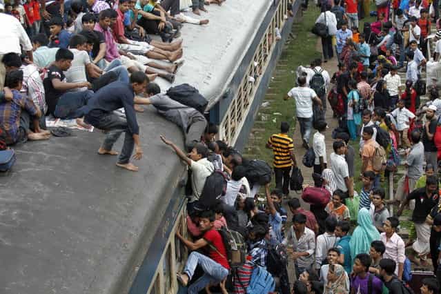 Passengers try to climb on board an overcrowded train at a railway station in Dhaka August 8, 2013. Millions of residents in Dhaka are travelling home from the capital city to celebrate the Muslim Eid al-Fitr holiday, which marks the end of the holy fasting month of Ramadan. (Photo by Andrew Biraj/Reuters)