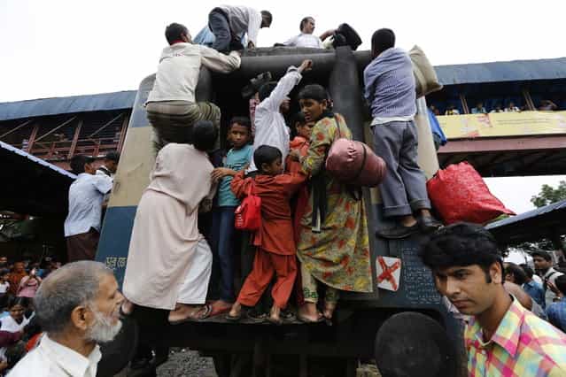 Passengers climb on board an overcrowded train at a railway station in Dhaka August 8, 2013. Millions of residents in Dhaka are travelling home from the capital city to celebrate the Muslim Eid al-Fitr holiday, which marks the end of the holy fasting month of Ramadan. (Photo by Andrew Biraj/Reuters)