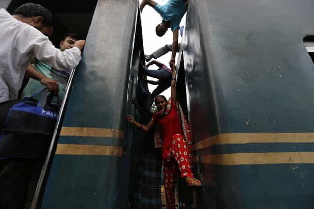 A woman tries to climb on board an overcrowded train at a railway station in Dhaka August 8, 2013. Millions of residents in Dhaka are travelling home from the capital city to celebrate the Muslim Eid al-Fitr holiday, which marks the end of the holy fasting month of Ramadan. (Photo by Andrew Biraj/Reuters)