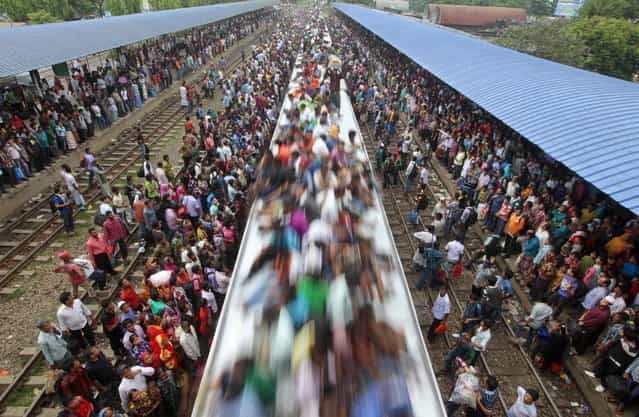Bangladeshi Muslims travel on the roof of a train to head home ahead of Eid al-Fitr as others wait at a railway station in Dhaka, Bangladesh, Thursday, August 8, 2013. Hundreds of thousands of people working in Dhaka to make a living return home to spend time with their family during Eid al-Fitr. (Photo by A.M. Ahad/AP Photo)