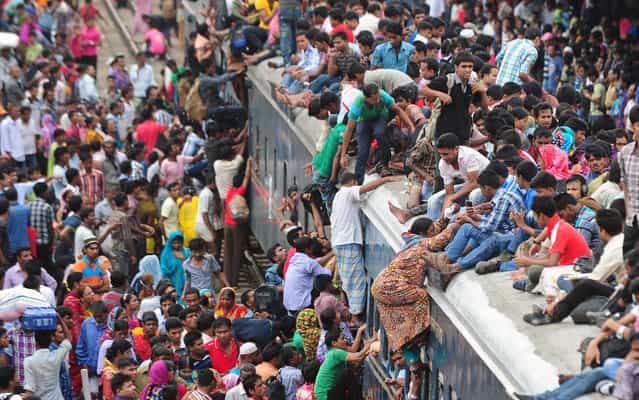 Passengers climb to board an overcrowded train at a railway station in Dhaka August 8, 2013. (Photo by Munir uz Zaman/AFP Photo)