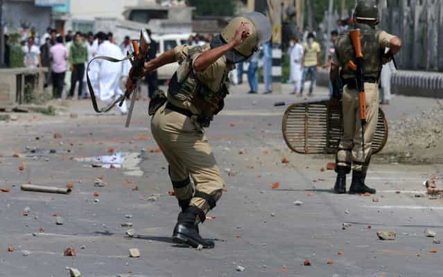 A Kashmiri paramilitary trooper throws a stone during a clash between protestors and Indian police officials in Srinagar on August 9, 2013. At least 30 people including 20 police were injured during clashes that broke out after Eid prayers in Srinagar, Indian Kashmir's main city, a police official and witnesses said. Indian police and paramilitary forces fired tear smoke shells and pallet guns at hundreds of protestors throwing rocks at them near the main prayer ground Eidgah in the old town area of the summer capital of the Himalayan state. (Photo by Tauseef Mustafa/AFP Photo)
