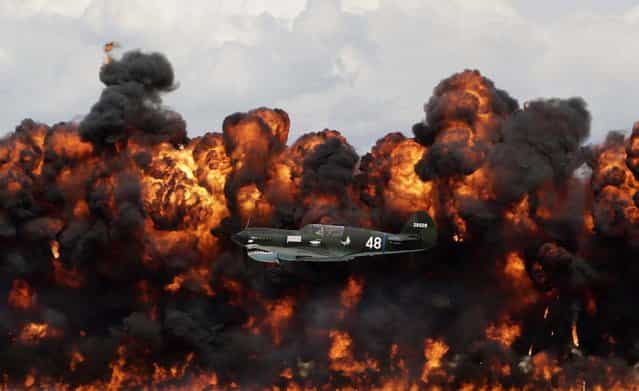 A World War II U.S. plane flies in front of a wall of fire as it takes part in a re-enactment of the attack on Pearl Harbor during an afternoon air show at the EAA AirVenture at Wittman Regional Airport in Oshkosh, Wisconsin, on August 3, 2013. (Photo by Darren Hauck/Reuters)